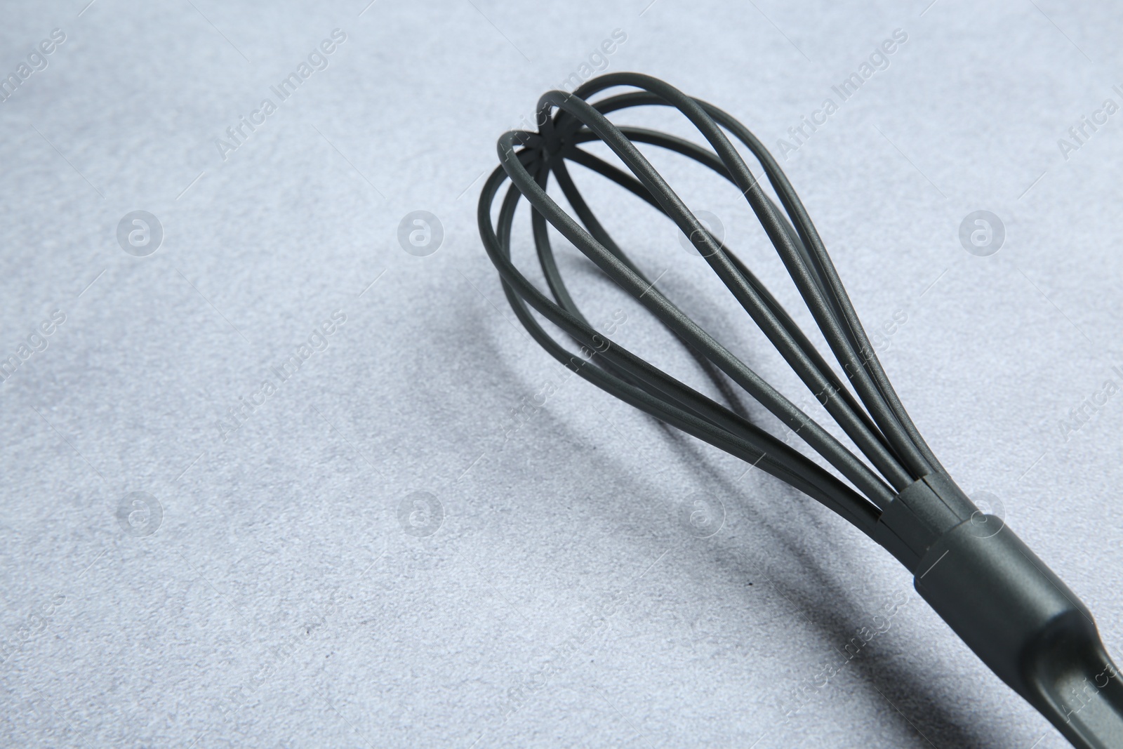 Photo of Plastic whisk on gray table, closeup. Space for text