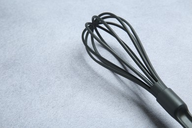 Photo of Plastic whisk on gray table, closeup. Space for text