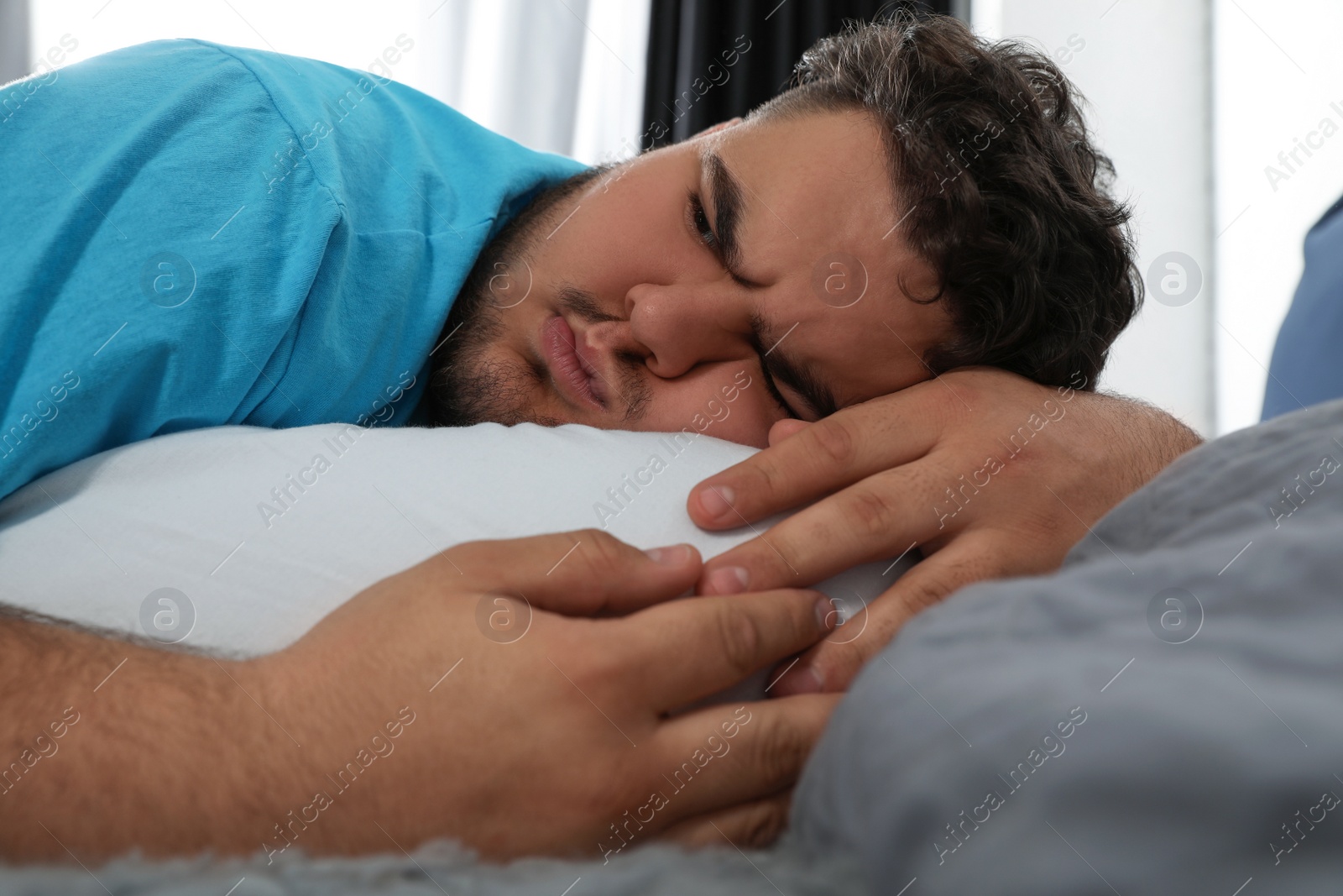 Photo of Depressed overweight man hugging pillow on bed