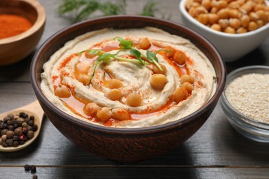 Photo of Delicious hummus with chickpeas and different ingredients on wooden table