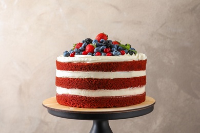 Stand with delicious homemade red velvet cake on color background