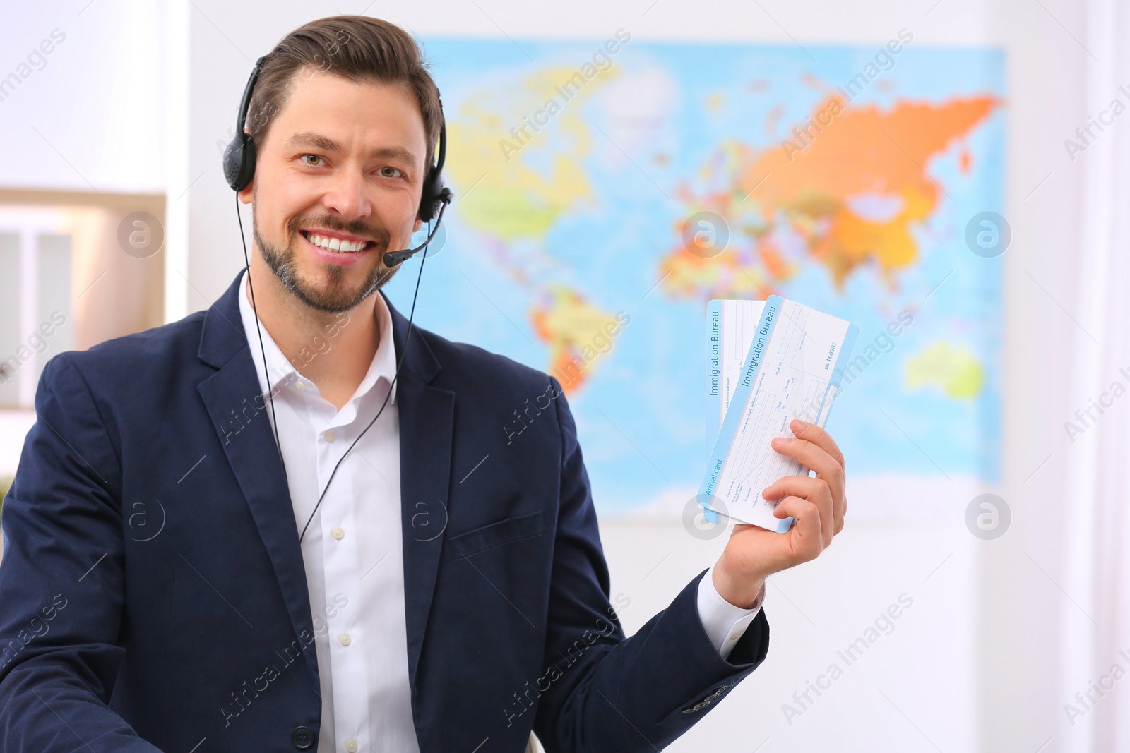 Photo of Male consultant with headset holding tickets in travel agency