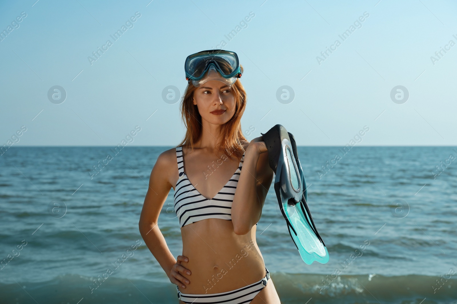 Photo of Woman with flippers and diving mask near sea on beach