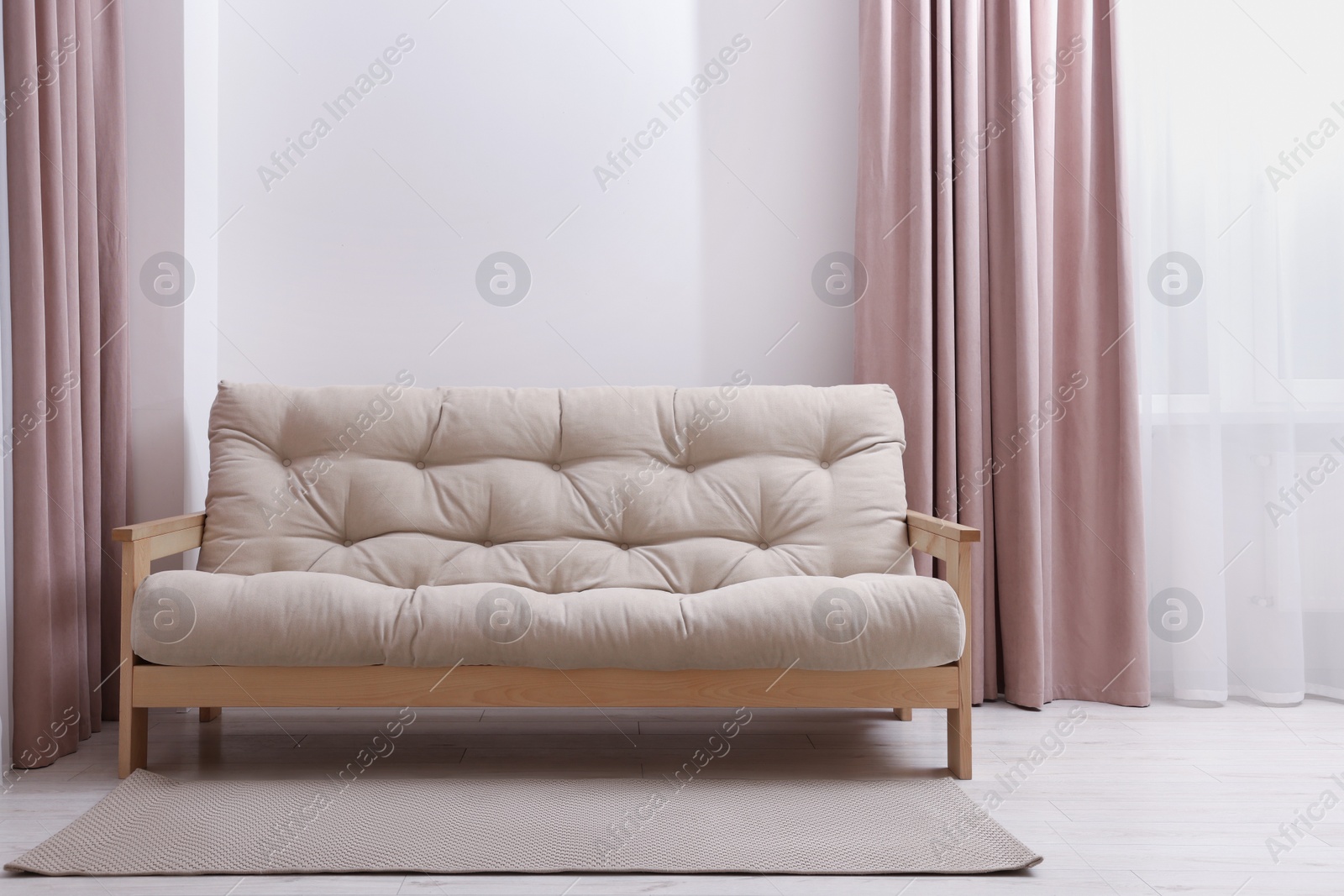 Photo of Comfortable sofa with rug in cozy light room. Interior design