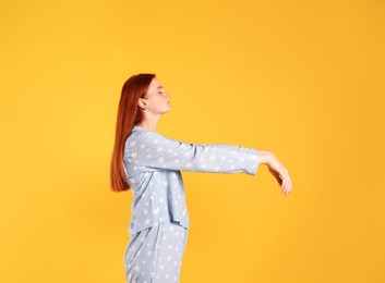 Photo of Young woman wearing pajamas in sleepwalking state on yellow background