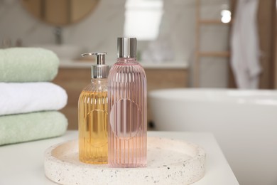 Photo of Bottles of shower gels and towels on white table in bathroom, space for text