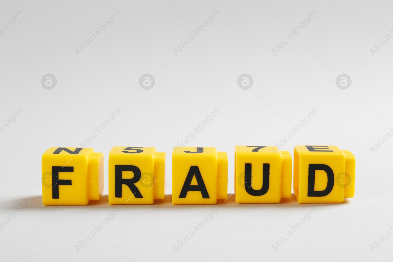 Photo of Word Fraud of yellow cubes with letters on light grey background