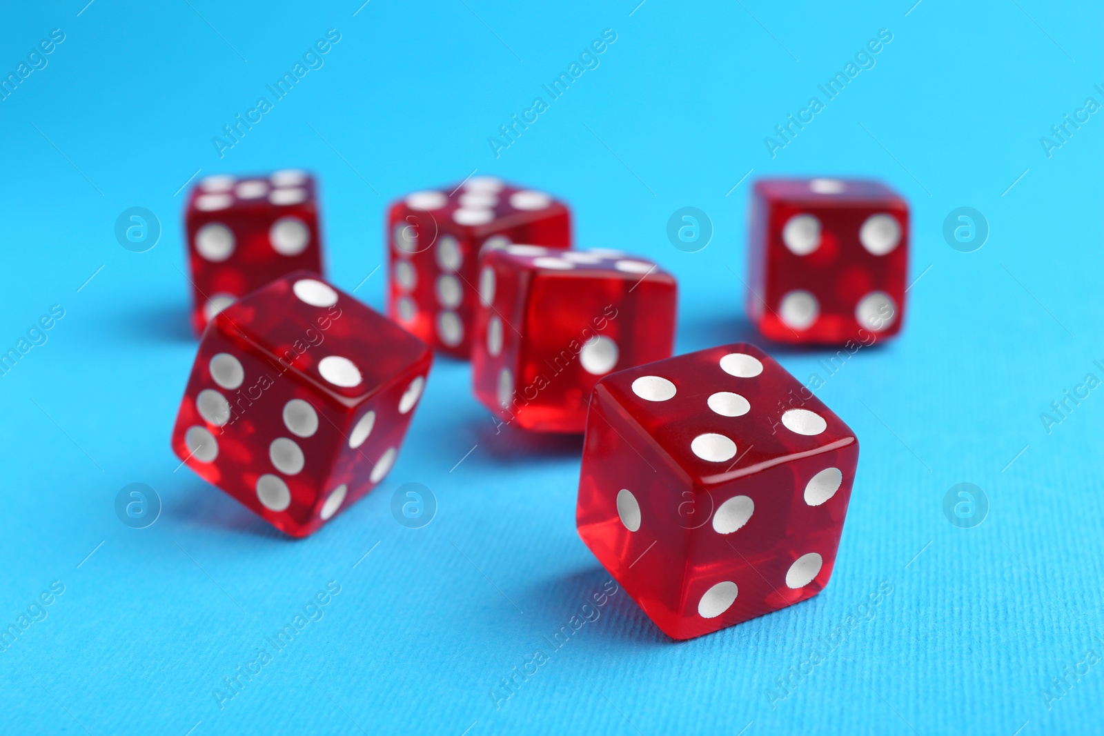 Photo of Many red game dices on light blue background, closeup