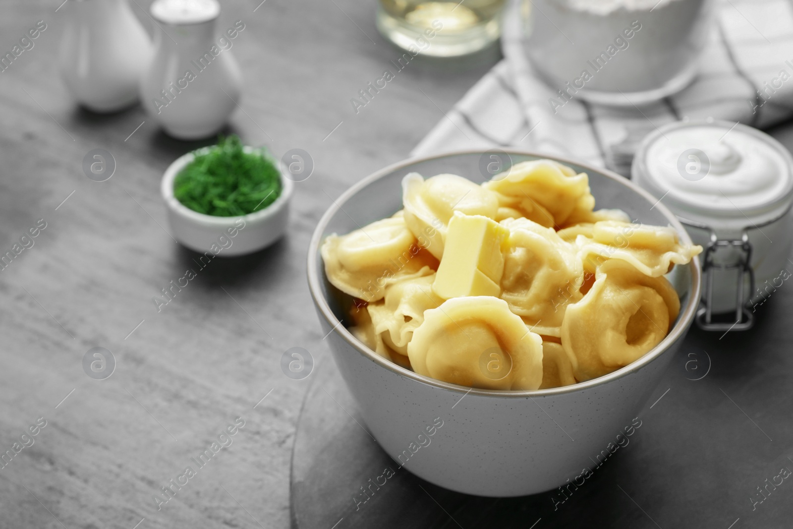 Photo of Tasty dumplings in bowl served on grey table, space for text