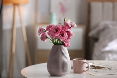 Photo of Vase with beautiful eustoma flowers on table in modern room interior