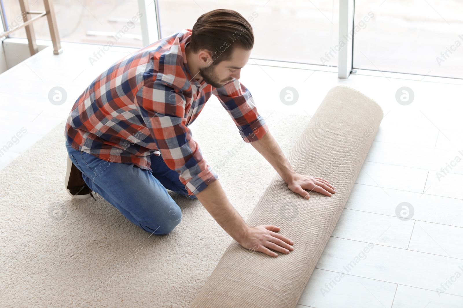 Photo of Man rolling out new carpet flooring in room