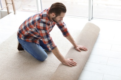 Man rolling out new carpet flooring in room