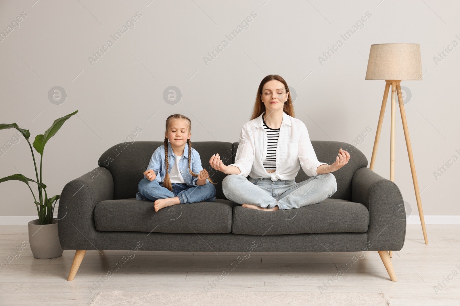 Photo of Mother with daughter meditating together at home. Harmony and zen