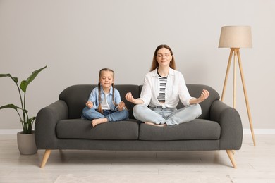 Mother with daughter meditating together at home. Harmony and zen