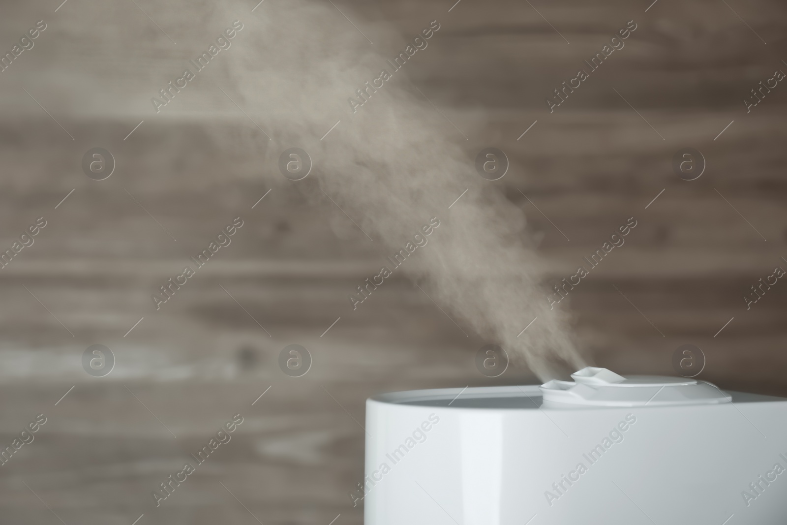 Photo of Modern air humidifier on wooden background, closeup. Space for text