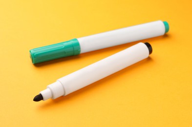 Photo of Bright color markers on orange background. Office stationery