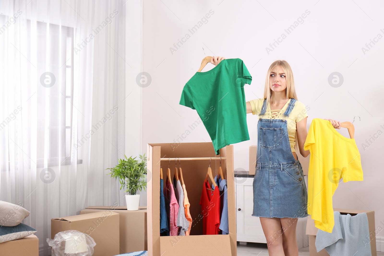 Photo of Young emotional woman near wardrobe box at home