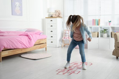 Cute little girl playing hopscotch at home