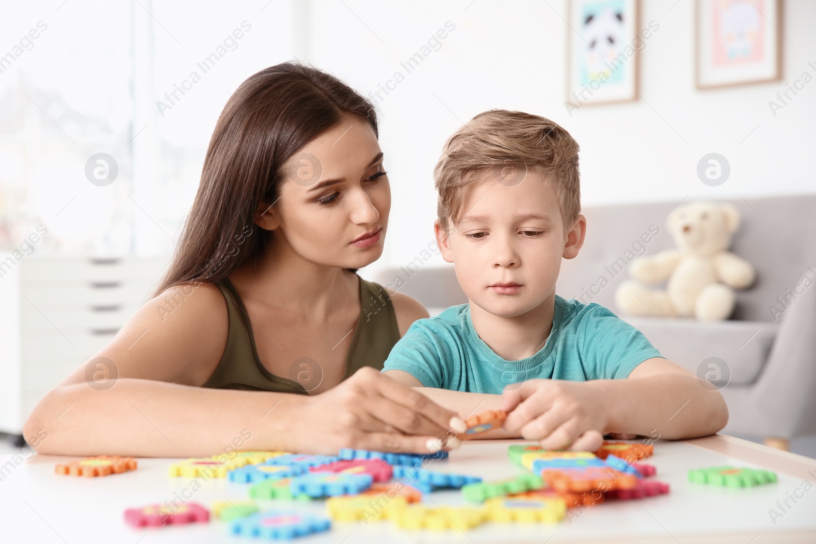 Photo of Young woman and little boy with autistic disorder playing at home