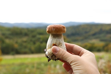 Photo of Man holding fresh wild mushroom on autumn day, closeup
