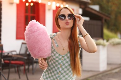 Beautiful woman with cotton candy outdoors on sunny day