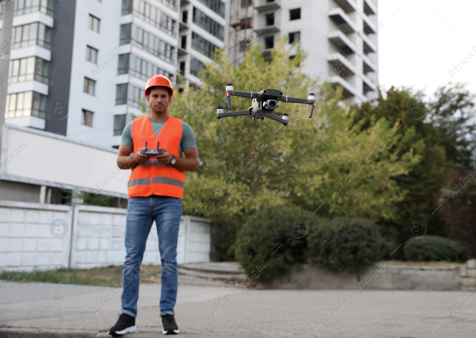 Photo of Builder operating drone with remote control at construction site. Aerial survey