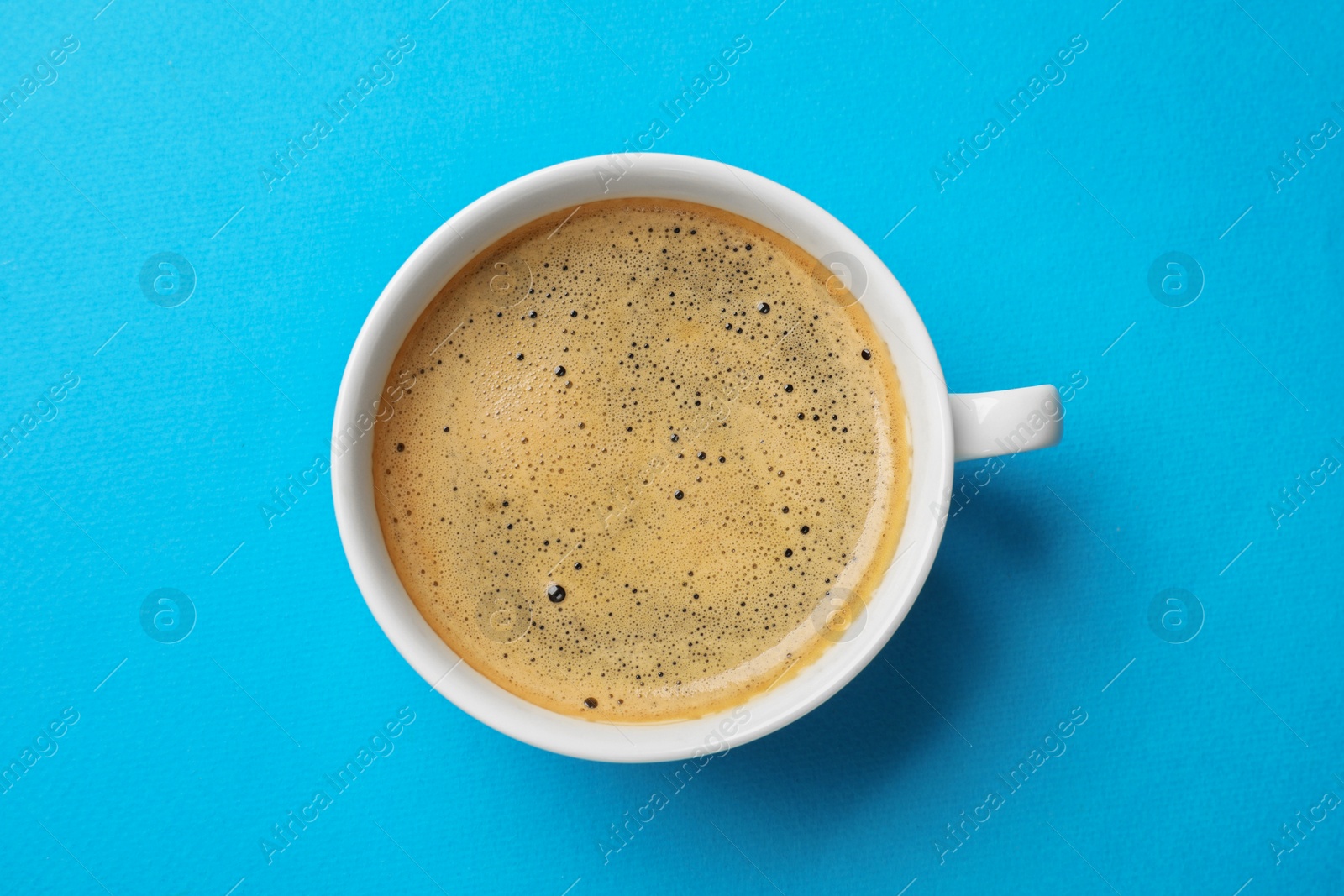 Photo of Aromatic coffee in cup on light blue background, top view