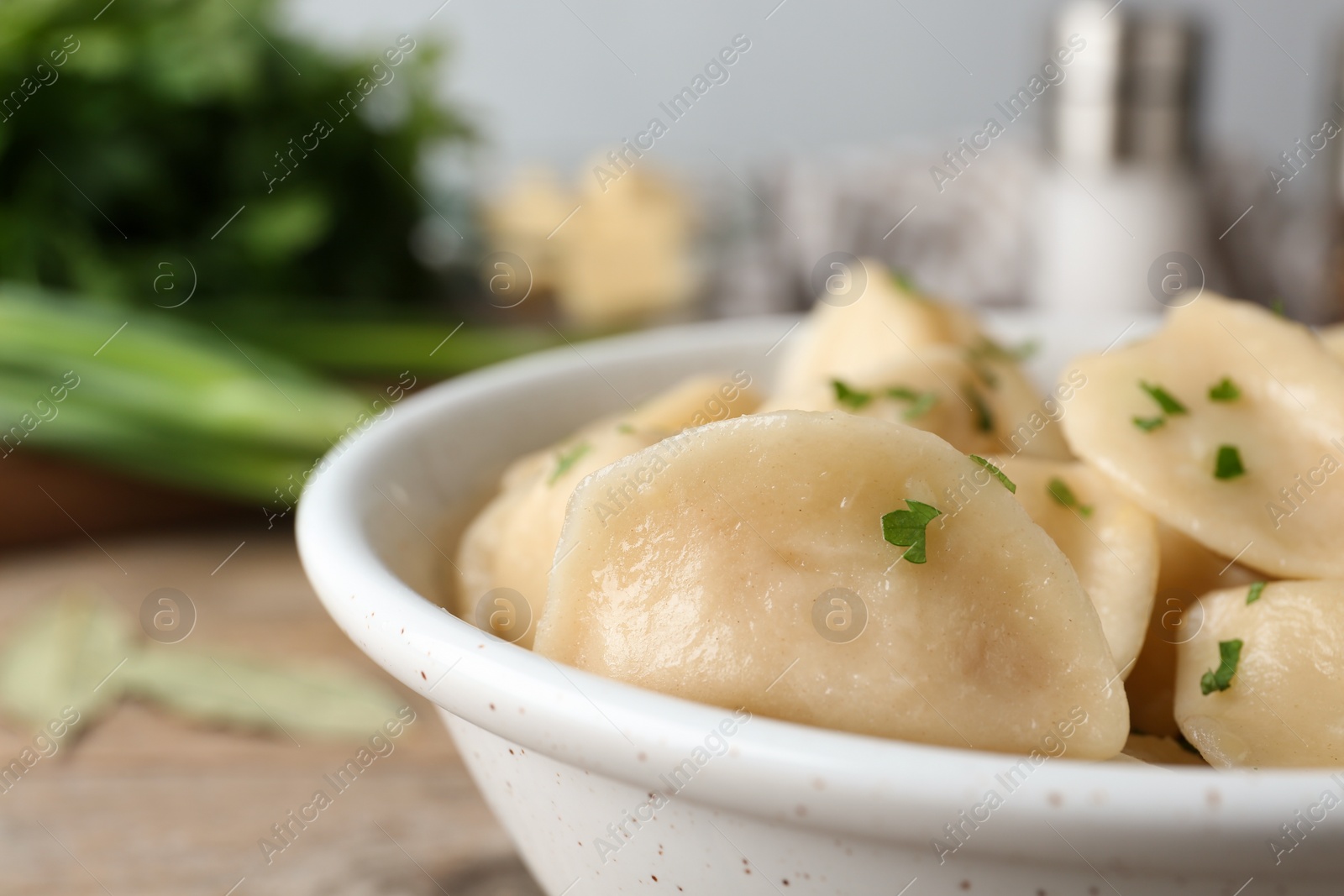 Photo of Bowl of delicious cooked dumplings on wooden table, closeup