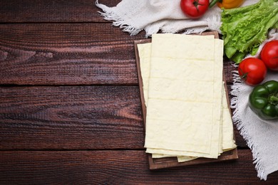 Photo of Delicious folded Armenian lavash and fresh vegetables on wooden table, flat lay. Space for text