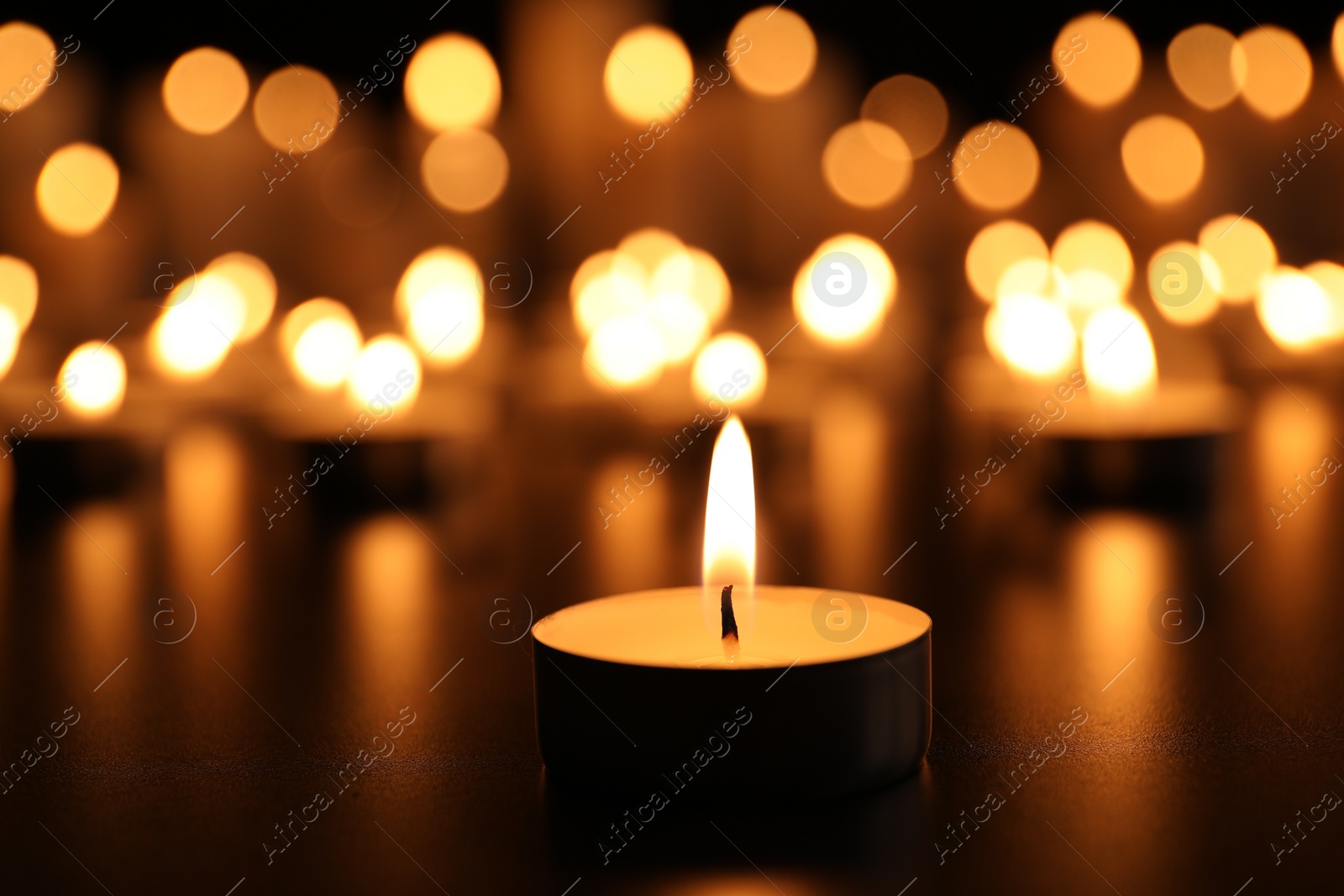 Photo of Burning candle on black table. Memory day