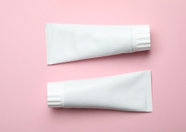 Photo of Blank tubes of toothpaste on color background, top view