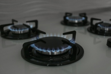 Gas burners with blue flame on modern stove. Space for text