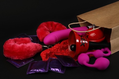 Photo of Shopping bag and different sex toys on black background