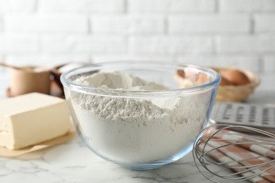 Photo of Making shortcrust pastry. Flour in bowl, butter and whisk on white marble table