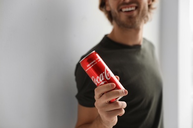 MYKOLAIV, UKRAINE - NOVEMBER 28, 2018: Young man with Coca-Cola can indoors, closeup. Space for text