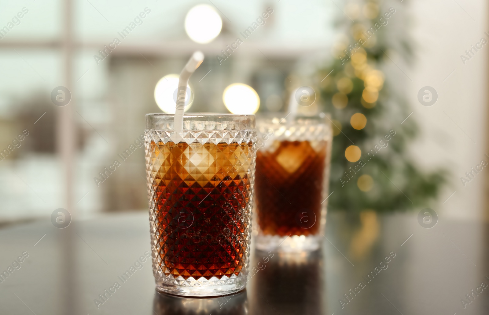 Photo of Glasses of cold cola on table against blurred background