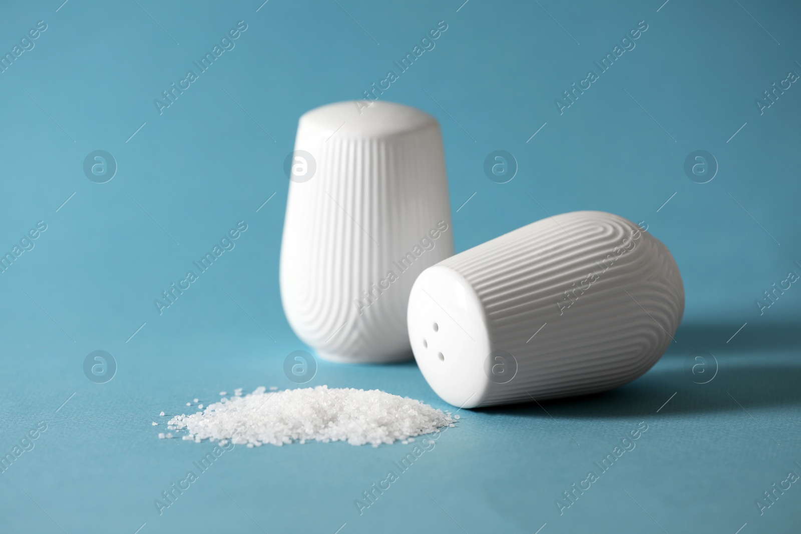 Photo of Organic salt and shakers on light blue background