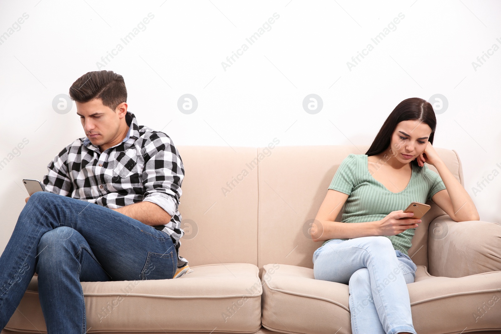 Photo of Couple addicted to smartphones ignoring each other at home. Relationship problems