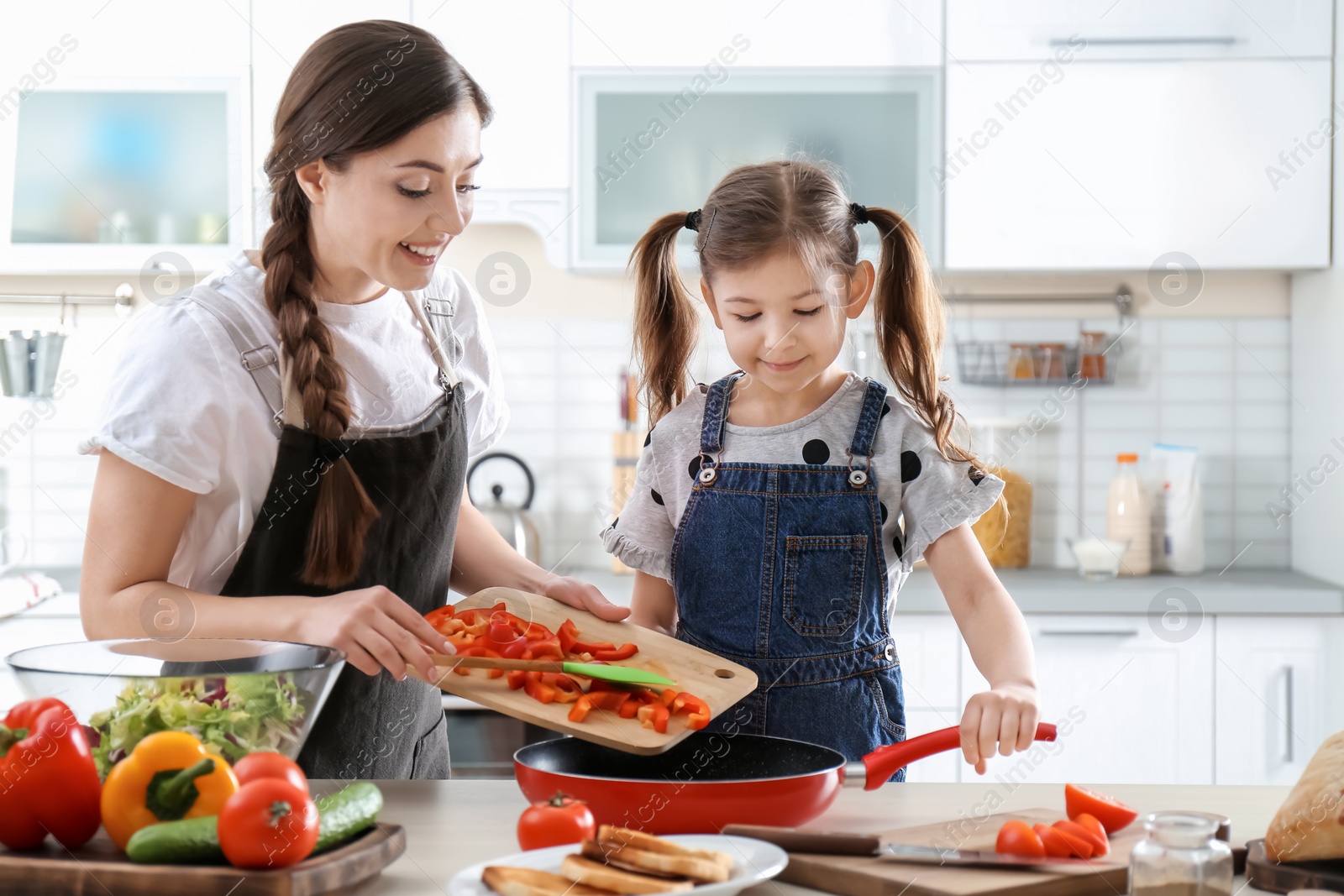 Photo of Young nanny with cute little girl cooking together in kitchen