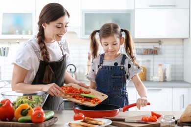 Photo of Young nanny with cute little girl cooking together in kitchen