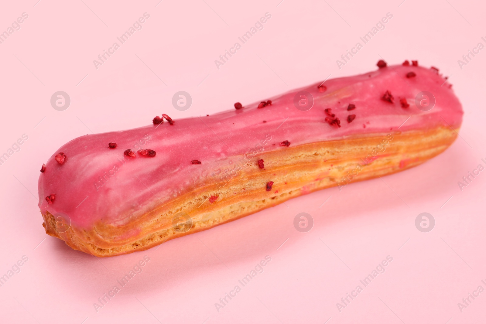 Photo of Delicious eclair covered with glaze on pink background