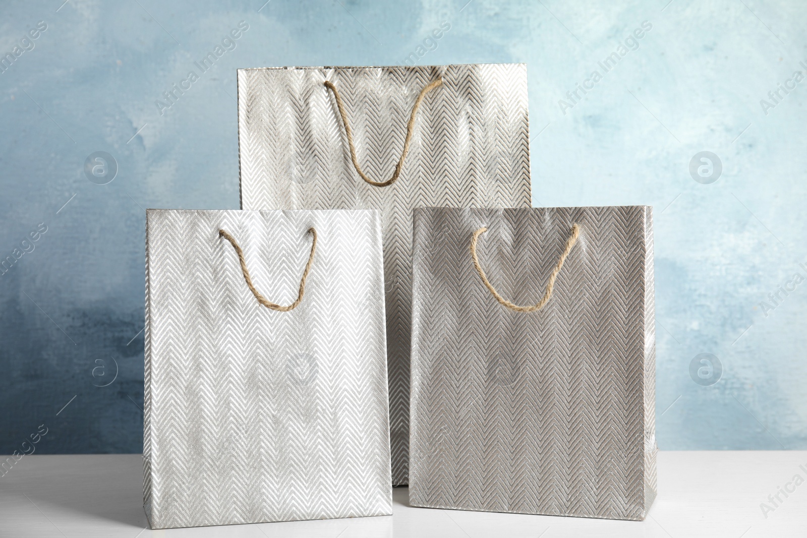 Photo of Silver shopping paper bags on white table