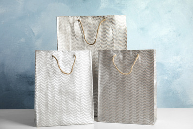 Photo of Silver shopping paper bags on white table