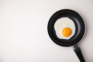 Tasty fried egg in pan on white background, top view. Space for text