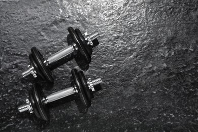 Photo of Barbells on dark textured floor, top view. Space for text