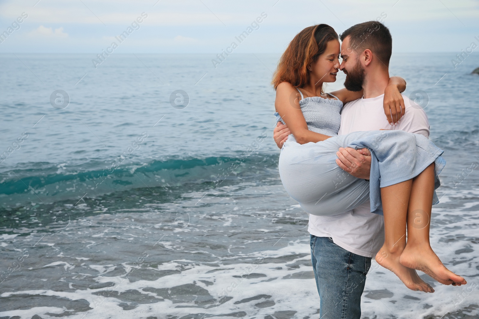 Photo of Young couple spending time together on beach near sea, space for text