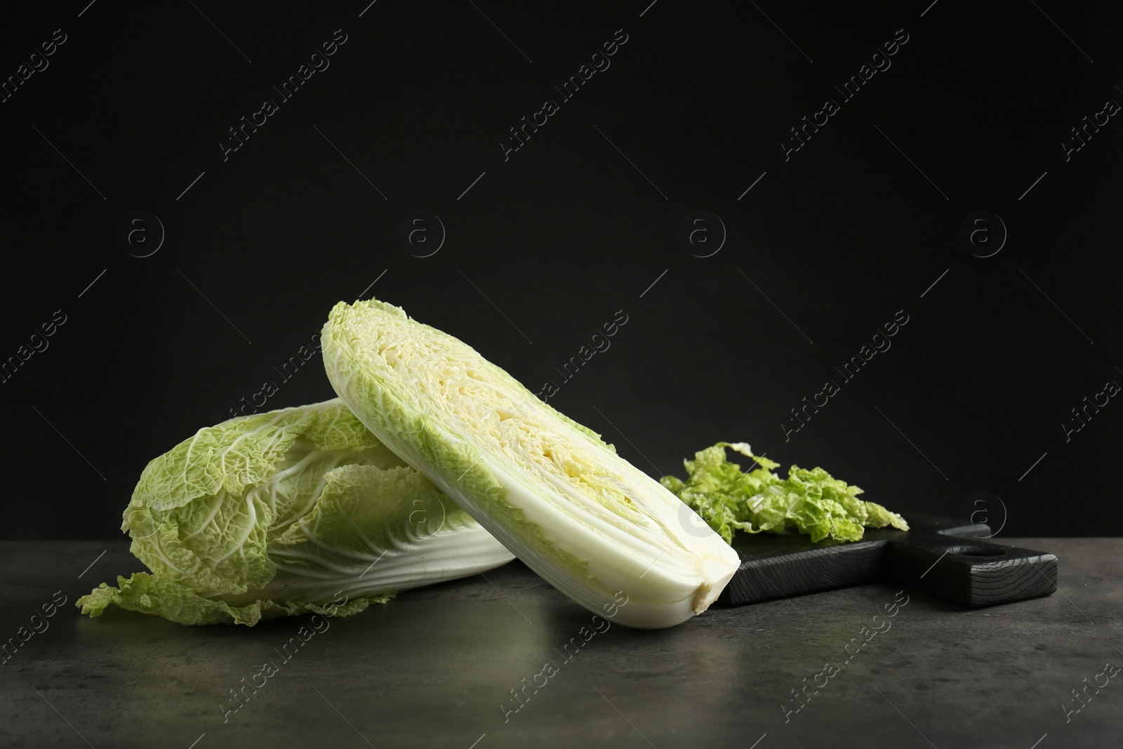 Photo of Whole and cut fresh Chinese cabbages on grey table