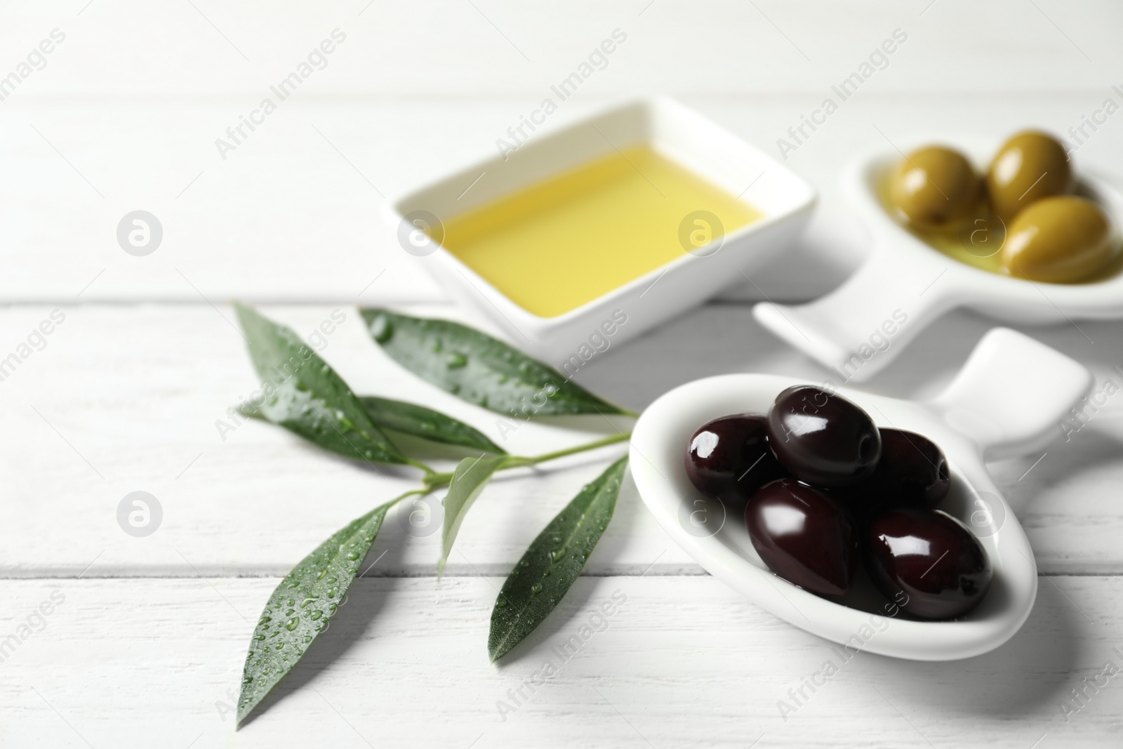 Photo of Bowls with olives and fresh oil on table