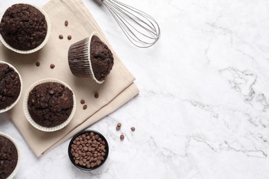 Photo of Tasty chocolate muffins on white marble table, flat lay. Space for text