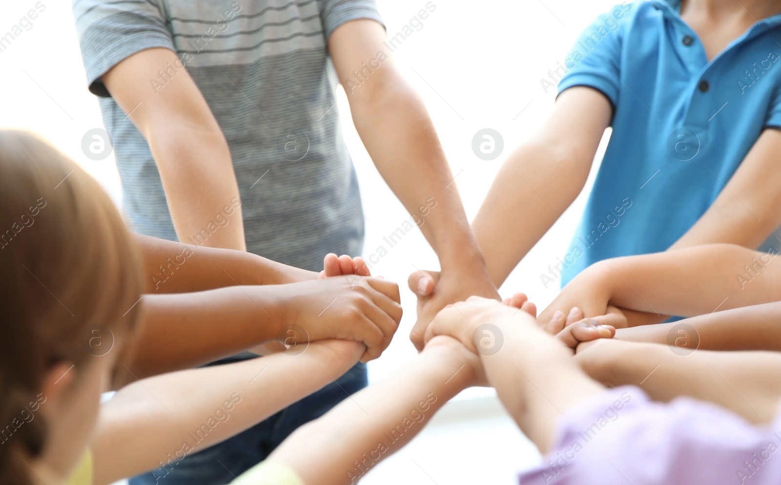 Photo of Little children holding their hands together on light background. Unity concept
